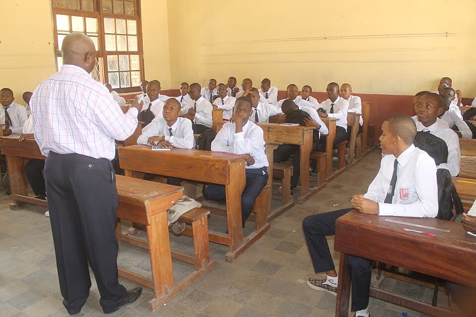 Photo : MONUSCO Photos, CC BY-SA 2.0, via Wikimedia Commons Un enseignant devant ses élèves dans une salle de classe à Kinshasa